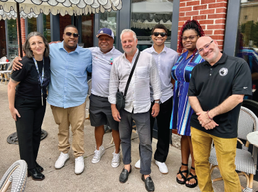 group of adults standing in a line smiling outside